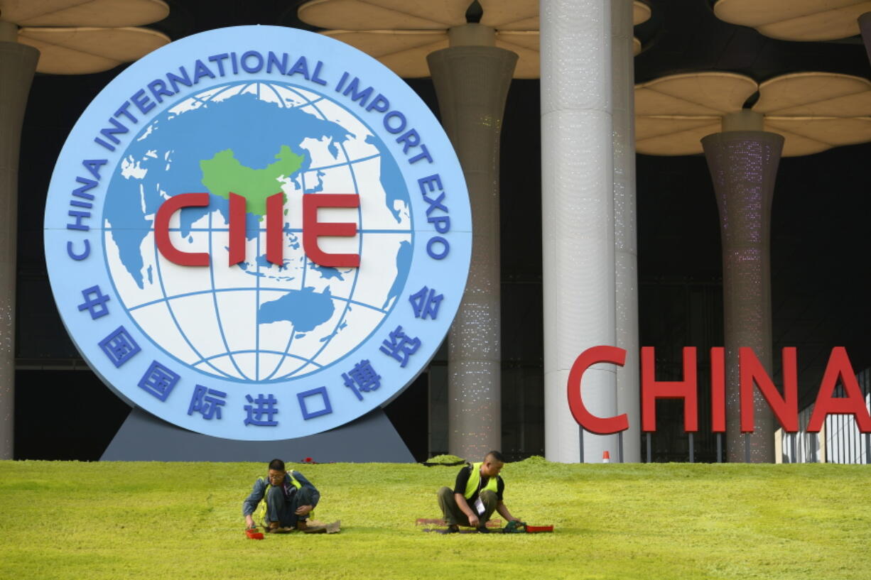 Workers trim the lawn at the National Exhibition and Convention Center in Shanghai, site of the China International Import Expo.