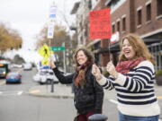 Tania Beaudet, left, and and M.J. McNeill hold signs encouraging people to vote in the midterms next to the King County Elections ballot drop box in Burien, Wash., Election Day, Tuesday, Nov. 6. 2018.