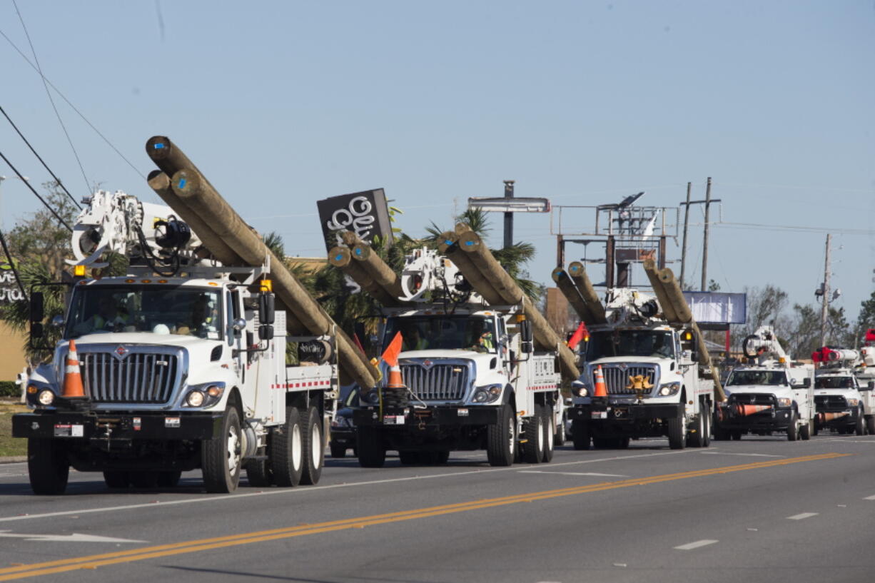 In this Oct. 13, 2018 photo Public Service Company of Oklahoma utility trucks deliver utility poles and trucks in Panama City, Fla.