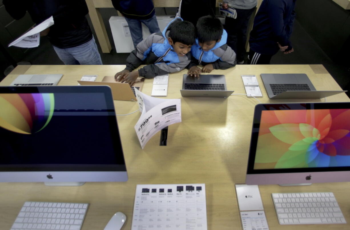 Eight-year-old twins Shalom Justin Kotha, left and Sammy Jayson Kotha, look at computers while they shop with their parents during an early Black Friday sale at a Best Buy store, Thursday, Nov. 22, 2018, in Overland Park, Kan.