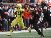 Oregon running back C.J. Verdell (34) tries to stiff-arm Oregon State safety Jalen Moore (33) on a run during the second half of an NCAA college football game in Corvallis, Ore., Friday, Nov. 23, 2018. Oregon won 55-15. (AP Photo/Timothy J.