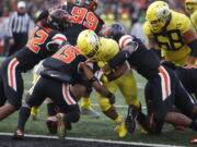 Oregon running back C.J. Verdell, center, bulls his way past Oregon State’s Doug Taumoelau (42), Jeffrey Manning Jr. (15) and Hamilcar Rashed Jr (right) for a touchdown in the first half of an NCAA football game in Corvallis, Ore., on Friday, Nov. 23, 2018. (AP Photo/Timothy J.