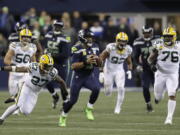 Seattle Seahawks quarterback Russell Wilson (3) scrambles away from Green Bay Packers defensive back Josh Jones (27) during the first half of an NFL football game Thursday, Nov. 15, 2018, in Seattle.