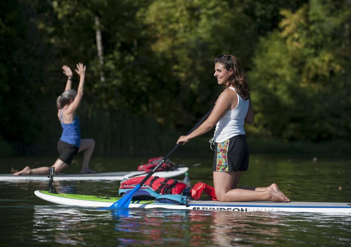 Teacher Angie Cherry, right, keeps an eye on the class while leading them through their yoga poses Thursday afternoon at Round Lake. Cherry will continue to teach some classes at Body Bliss Yoga Studio in Washougal, even after she transfers operations to teacher Jacquie Michelle.