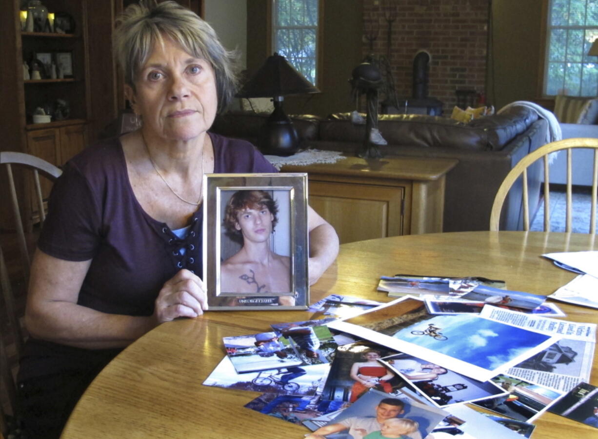 Linda Marino poses with photographs of her son, Samuel, at her home in Tolland, Conn. Samuel Marino died in a 2009 car crash that relatives believe was intentional after becoming a victim of a male sex trafficking ring. Advocates are calling for more recognition and services for male victims.