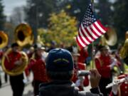 David Medrano, a Vancouver resident and Coast Guard veteran for service from 1972 to 1978, waves a flag as the Camas High School Papermaker Marching Band passes by Saturday in the 32nd annual Lough Legacy Veterans Parade in Vancouver.