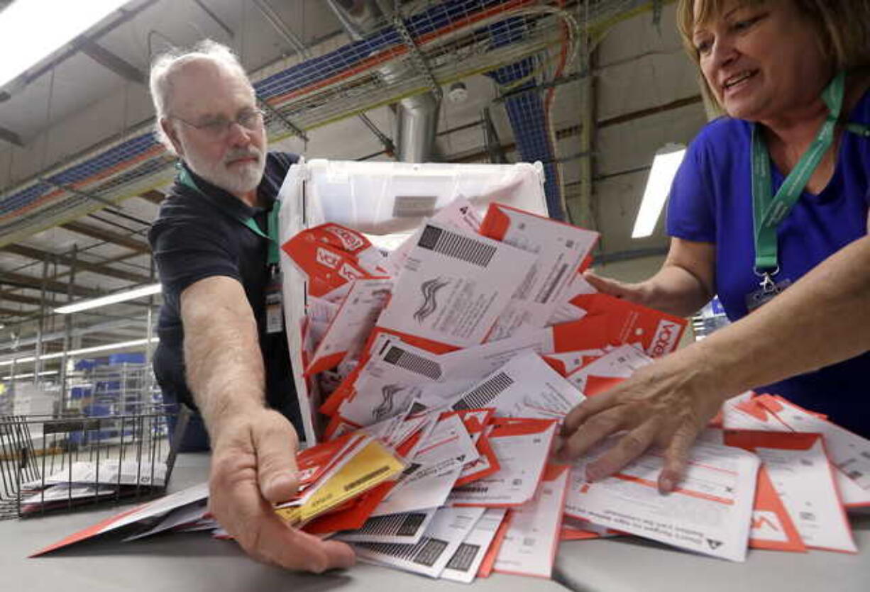 Election workers Mark Bezanson, left, and Julie Olson dump ballots collected earlier in the day from drop boxes onto a table for sorting at the King County Elections office, Monday, Nov. 5, 2018, in Renton, Wash. Voters in Washington all vote only by mail.