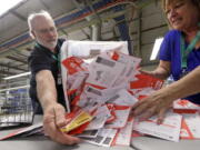 Election workers Mark Bezanson, left, and Julie Olson dump ballots collected earlier in the day from drop boxes onto a table for sorting at the King County Elections office, Monday, Nov. 5, 2018, in Renton, Wash. Voters in Washington all vote only by mail.