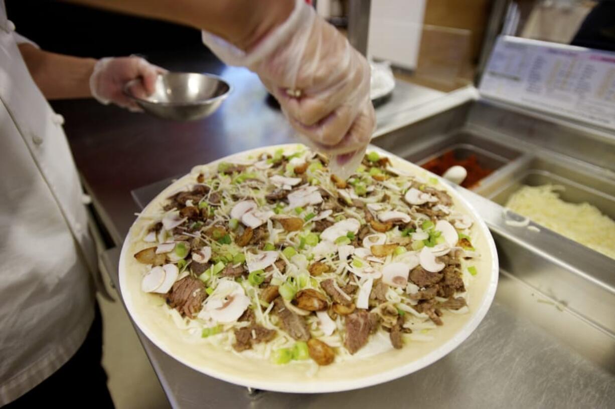 A Papa Murphy's employee prepares a take-and-bake pizza.