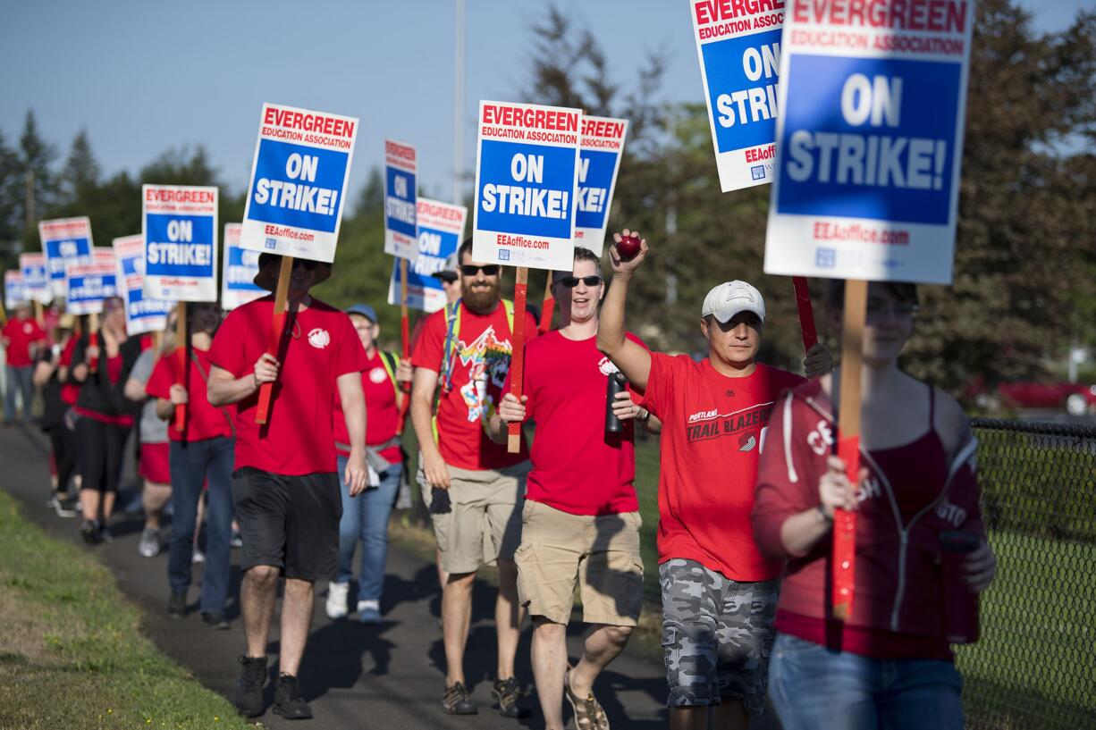 Evergreen High School physical education and health teacher Gabe Nunez, white hat, holds an apple high while joining fellow educators in picketing outside the school on Tuesday morning, Aug. 28, 2018. Nunez was among the hundreds of local teachers that took to the picket line amidst contract negotiations. "We are here to create a better future for new educators and present educators," he said.