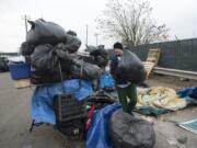 William Burke collects his belongings in black trash bags Nov. 21 while moving off his camping spot near Share House in downtown Vancouver.