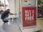 Lids Sales Associate Tavi Pikmey cleans the window of Lids at the Vancouver Mall on Nov. 19. Retail saw big jobs gains in Clark County in November.