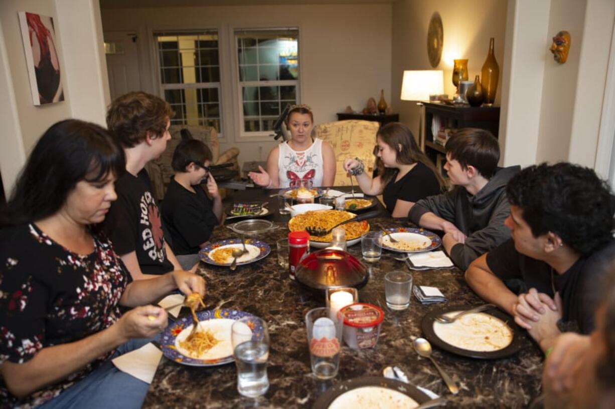 Leesa Holder,center, recounts her family’s experience as they tried to reunite and escape the fire that destroyed Paradise, Calif., in November. Holder and her two children, Dominick Brown, third from left, 13, and Amber Brown, third from right, 14, came to live with the family of Battle Ground’s Lois Ivanoff, left, after they were displaced by the fire.