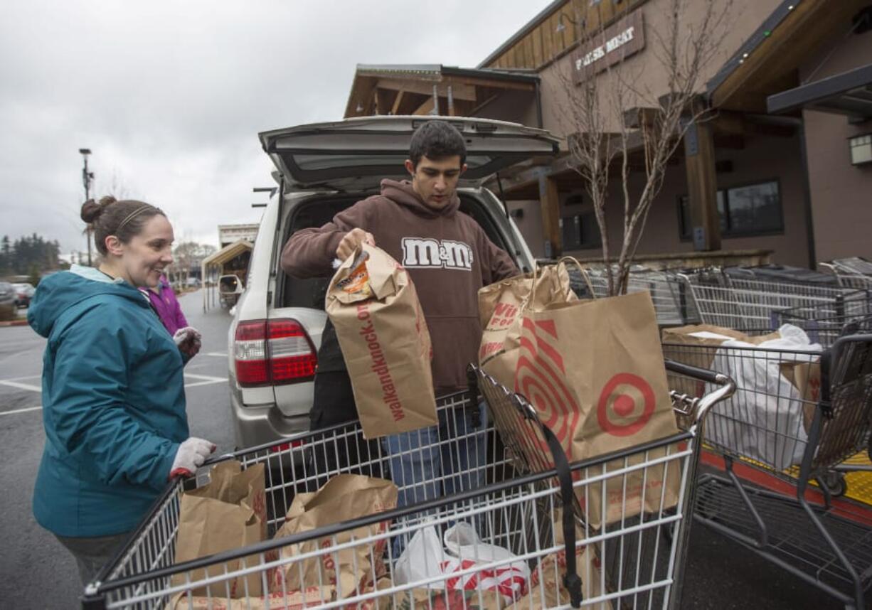 Volunteers Heidi Kartchner, left, and Noah Sarkissian help unload a car filled with Walk & Knock food donations in the parking lot at Chuck’s Produce in Salmon Creek in December 2018.