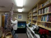 Anthony Moreno, a volunteer, installs a Christmas tree inside the library at the Fort Vancouver Seafarers Center. The center held its annual Christmas party Sunday, with about 50 people in attendance.