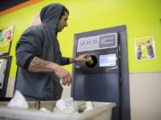 Jeremy Bailey, a Portland resident, drops an empty into a reverse vending machine at the Delta Park BottleDrop. He says he brings his bottles and cans about once a month to get extra money for gas.