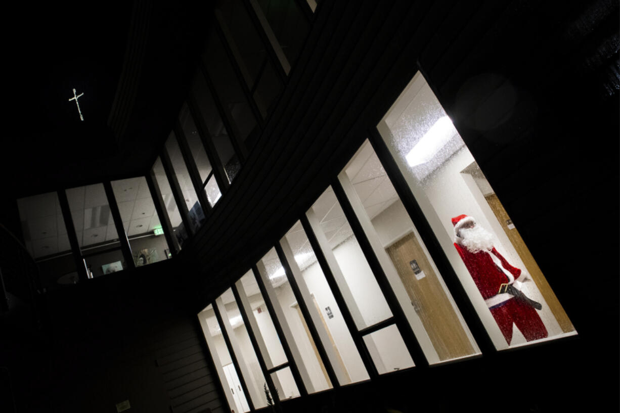 Volunteer Aaron Mabey, dressed as Santa Claus, walks between storage areas on the ground floor of Vancouver United Church of Christ in Hazel Dell while preparing free meals for Martha’s Pantry, which will distribute the food and goodies in time for Christmas.