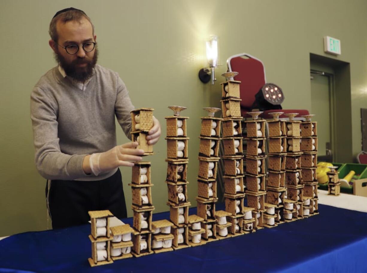 Rabbi Shmulik Greenberg assembles a menorah out of s’mores Sunday at the Chabad Jewish Center’s celebration Sunday evening marking the conclusion of Hanukkah.