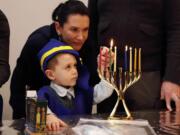 Four-year-old Ozzie Eichler lights a menorah with his mother, Julie Eichler, at the Chabad Jewish Center on Sunday, which was the last night of the eight-night Festival of Lights.