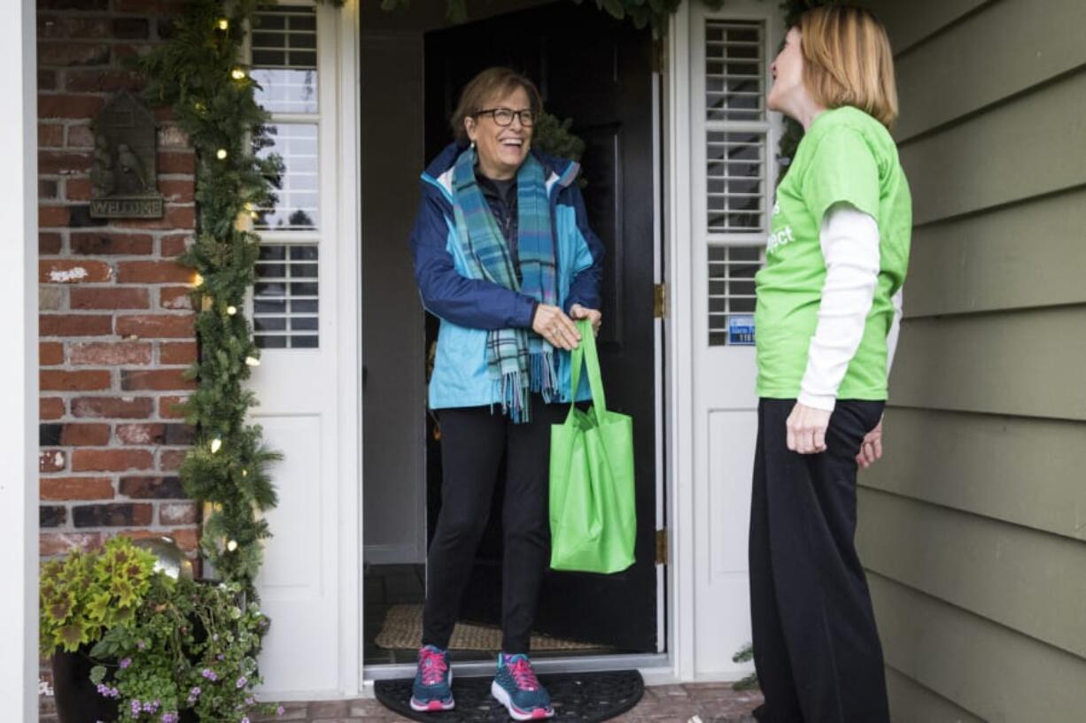 Mary Beth Nelson, left, hands her bag of food donations to Kathy Hampton on Dec. 8 in Clark County. Hampton volunteers every other month for the Clark Neighbors Food Project, which provides a steady supply of food to local pantries.