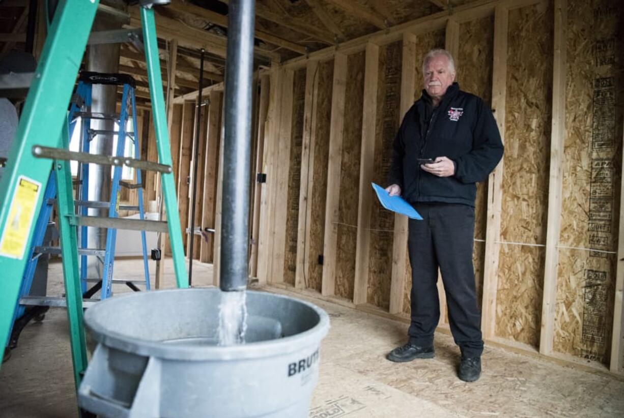 Fire Marshal Ron Schumacher does a bucket test to make sure the fire sprinkler system has adequate water output in a new home in Camas. Two sprinklers must provide at least 26 gallons of water in one minute to pass the test.