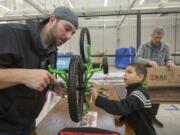 Rylan Ward, 7, and his stepfather Justin Gilson assemble a bike as part of the Scott Campbell Christmas Promise event in Vancouver Saturday. The bicycles will be distributed to needy kids around Clark County.