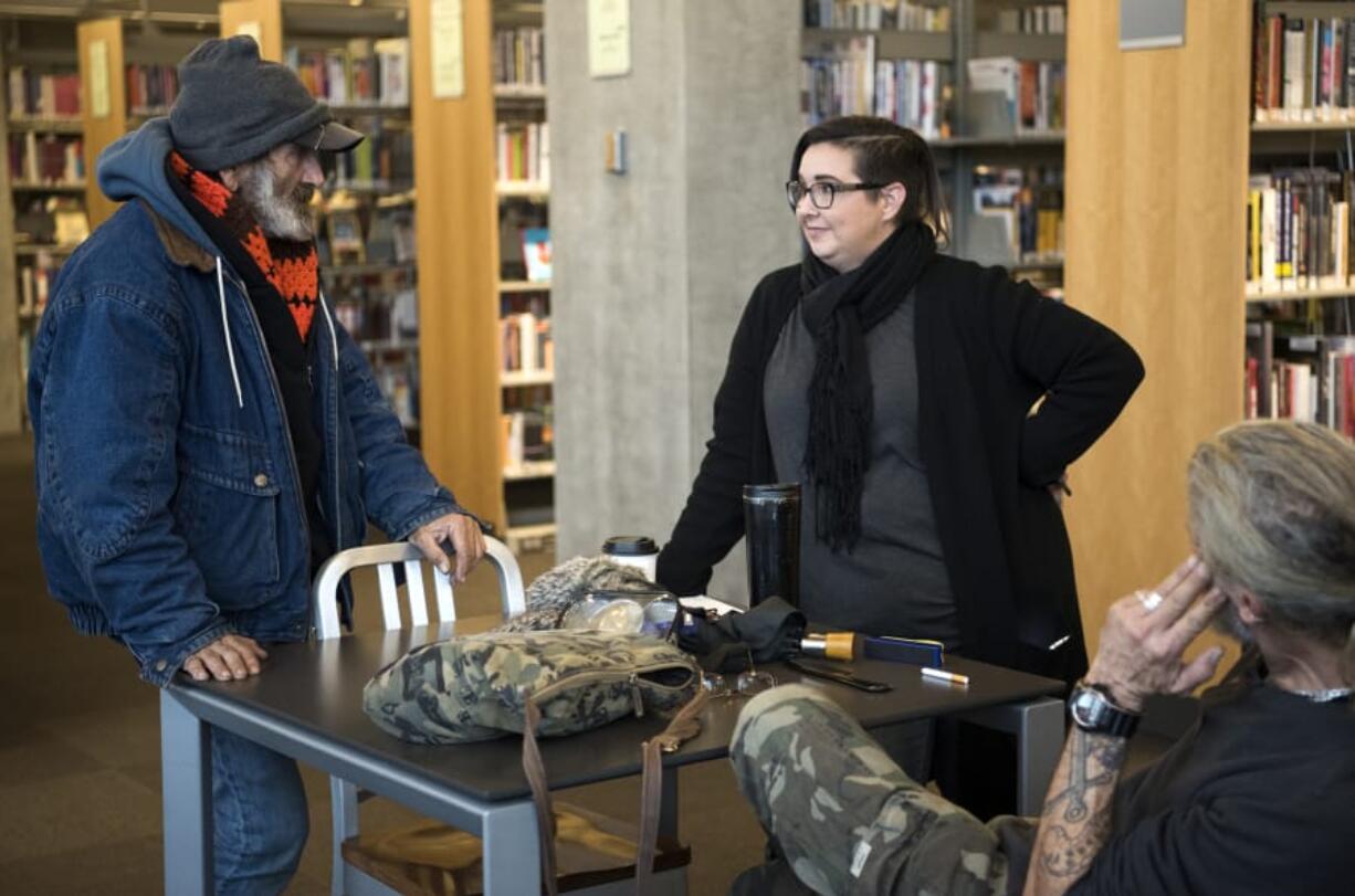 Jack Crowley, left, talks with Jamie Spinelli, center, a case manager with Community Services Northwest, at the Vancouver Community Library on Dec. 11. As part of a new pilot project, Spinelli works in the library every Tuesday morning to help connect homeless people, like Crowley, with resources. “The library staff here are excellent, but they’re also not social workers,” Spinelli said.