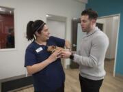 Licensed veterinary technician Karina McNulty, left, greets four-legged patient, Sumo, while talking with Sumo’s owner Allon Freiman. Freiman is the CEO of Petriage, an online pet health service that partners with WellHaven Pet Health.