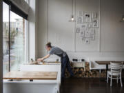 Madison Loveall of Vancouver clears tables after the lunchtime rush at Nonavo Pizza in downtown Vancouver. Nonavo owner Joey Chmiko says the upcoming minimum wage increase won’t directly affect the restaurant, which already uses $12 per hour as its starting salary for all employees.