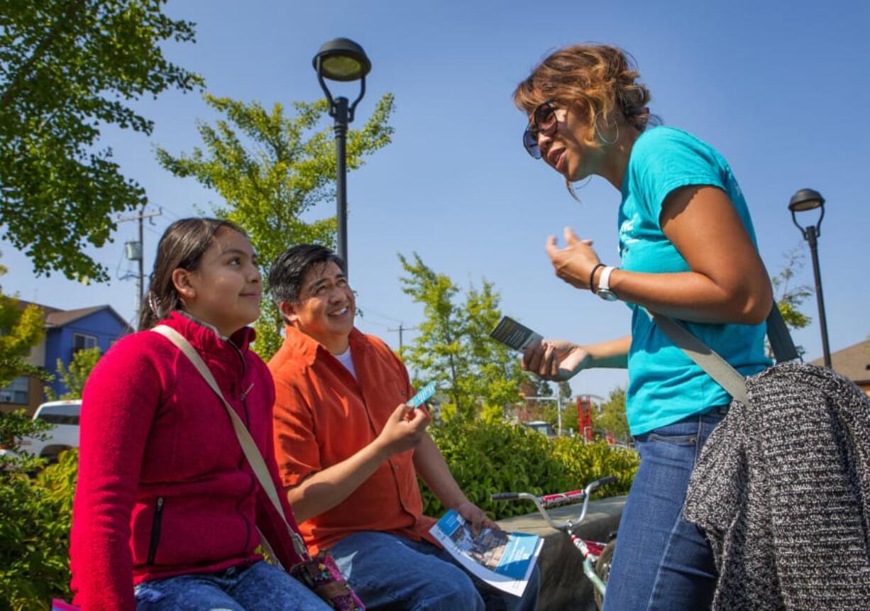 Darany Pen, right, a talent development specialist with Highline Public Schools, speaks with Roberto Santos and his daughter Alejandra Santos, 11, at a family resource fair in White Center. Ellen M.