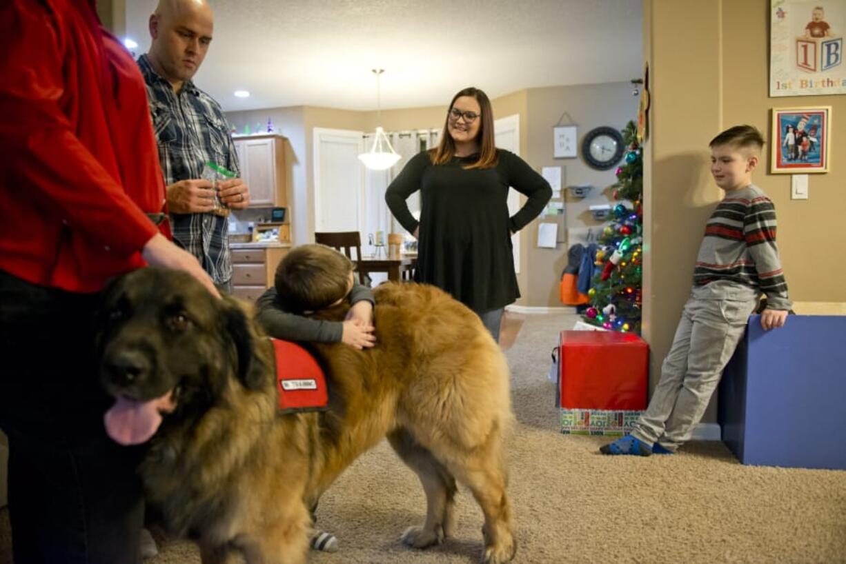 Service-dog-in-training Valor is hugged by Asher Montes, 4, while visiting with Kirsten Becker, the executive director of Autism Anchoring Dogs.