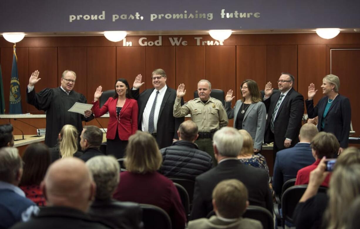 Under the gaze of families and supporters, Clark County Superior Court Judge David Gregerson, left, swears in (from left) Alishia Topper, Peter Van Nortwick, Chuck Atkins, Temple Lentz, Scott Weber and Julie Olson into their respective terms in office in Clark County government.