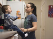 Brodie Riggan, 2, drinks juice under the watchful eye of his mother, Kayla Stotts, on Friday night. Her two youngest sons spend the weekdays in child care, and Stotts said she tries to focus on her kids in the evenings. “It’s hard, because they want my attention. They’ve been without mom all day,” she said.