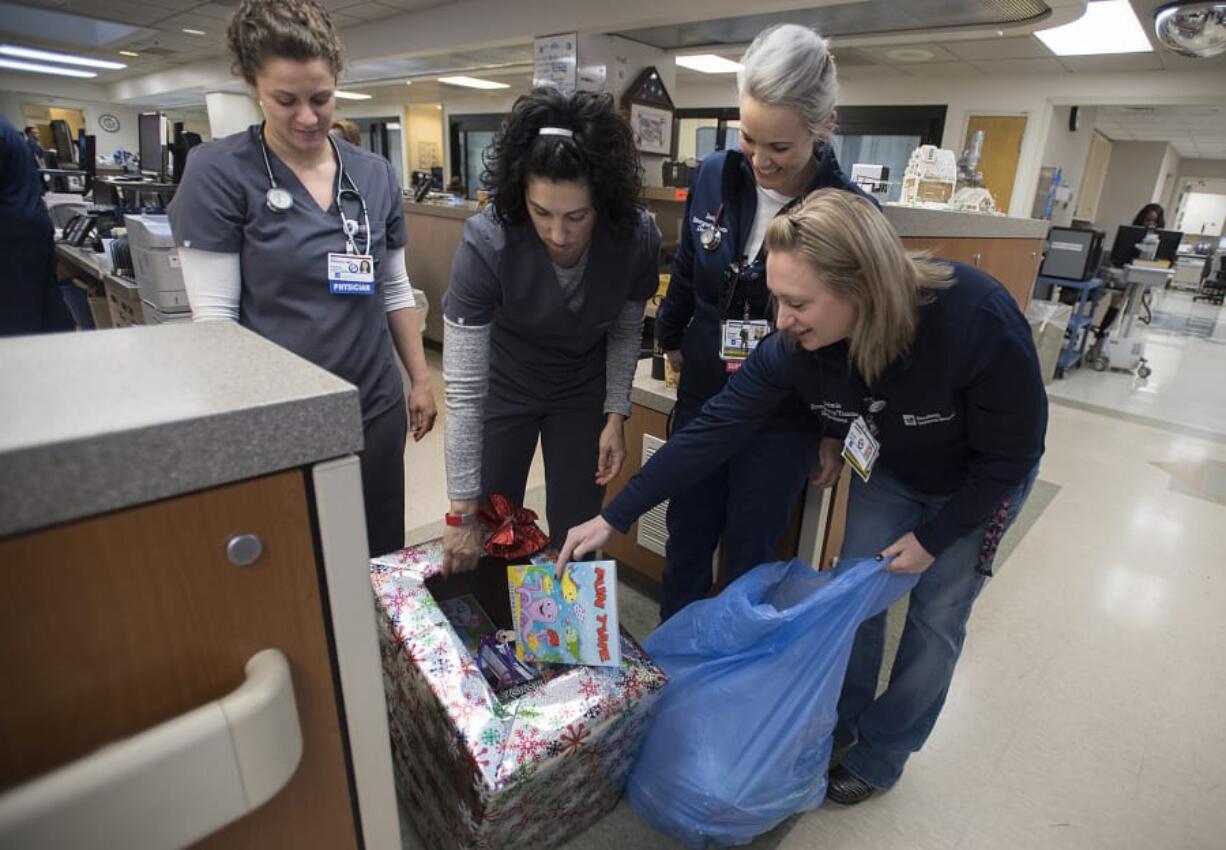 Dr. Erin Baldwin, from left, Dr. Dina Brothers, registered nurse Desiree Kauffman and registered nurse Jaimie Mogush look over toys donated for children in the emergency room at PeaceHealth Southwest Medical Center on Thursday morning.