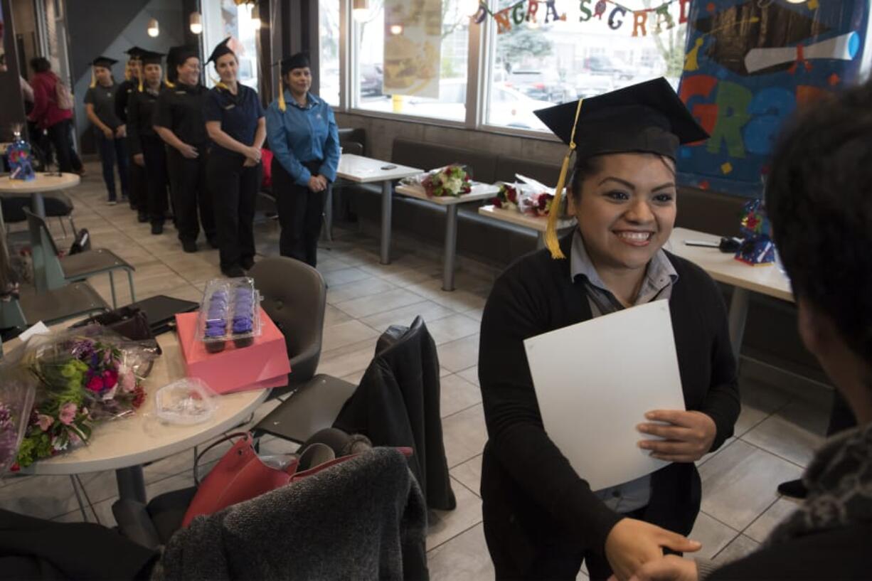 Jazmin Betancourt, a store manager at the Stockford Village McDonald’s, collects her diploma during an English Under the Arches graduation ceremony on Monday at the McDonald’s at 2814 N.E. Andresen Road. Betancourt was among 10 graduates in the course that teaches students to learn English or improve their skills.