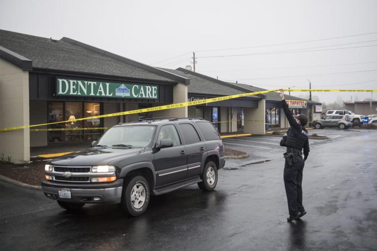 A Vancouver police officer lifts crime scene tape to allow a vehicle to leave the scene of a fatal shooting Monday afternoon at Pacific 63 Center in Hazel Dell.