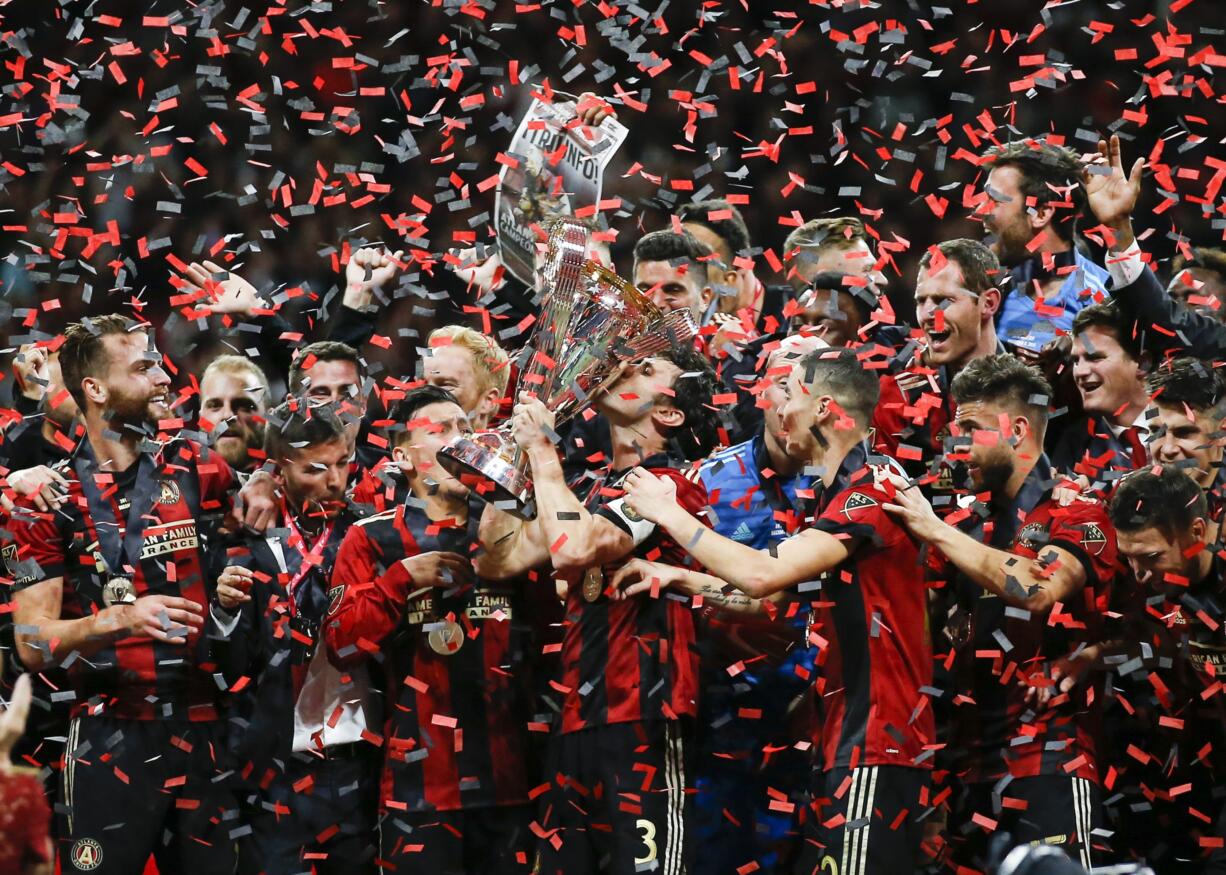 Atlanta United team captain Michael Parkhurst (3) kisses the trophy as teammates celebrate during the trophy presentation after the MLS Cup championship soccer game against the Portland Timbers, Saturday, Dec. 8, 2018, in Atlanta. Atlanta United won 2-0.