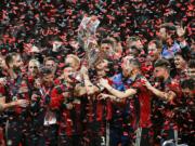 Atlanta United team captain Michael Parkhurst (3) kisses the trophy as teammates celebrate during the trophy presentation after the MLS Cup championship soccer game against the Portland Timbers, Saturday, Dec. 8, 2018, in Atlanta. Atlanta United won 2-0.