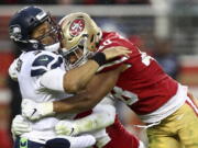 Seattle Seahawks quarterback Russell Wilson, left, is hit after passing by San Francisco 49ers linebacker Fred Warner, right, and linebacker Elijah Lee, bottom, during the second half of an NFL football game in Santa Clara, Calif., Sunday, Dec. 16, 2018.