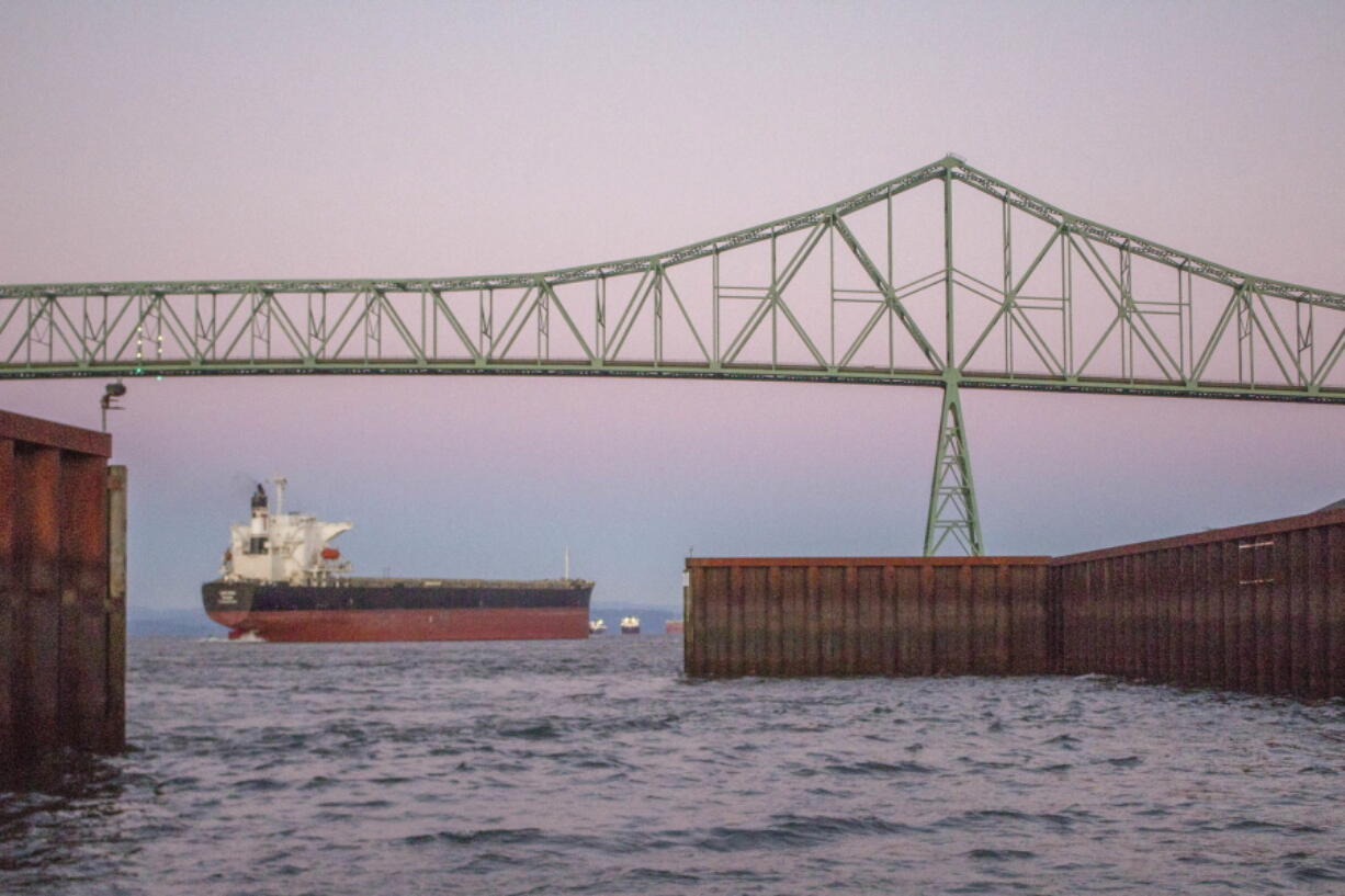 A cargo ship passes under the Astoria Bridge near Astoria, Ore., on Dec. 8. The cash-strapped Port of Astoria is considering charging fees to passing ships to raise money despite objections from the shipping industry.