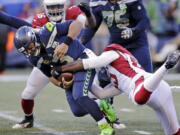 Seattle Seahawks quarterback Russell Wilson, left, is sacked by Arizona Cardinals’ Chandler Jones, right, during the first half of an NFL football game, Sunday, Dec. 30, 2018, in Seattle.