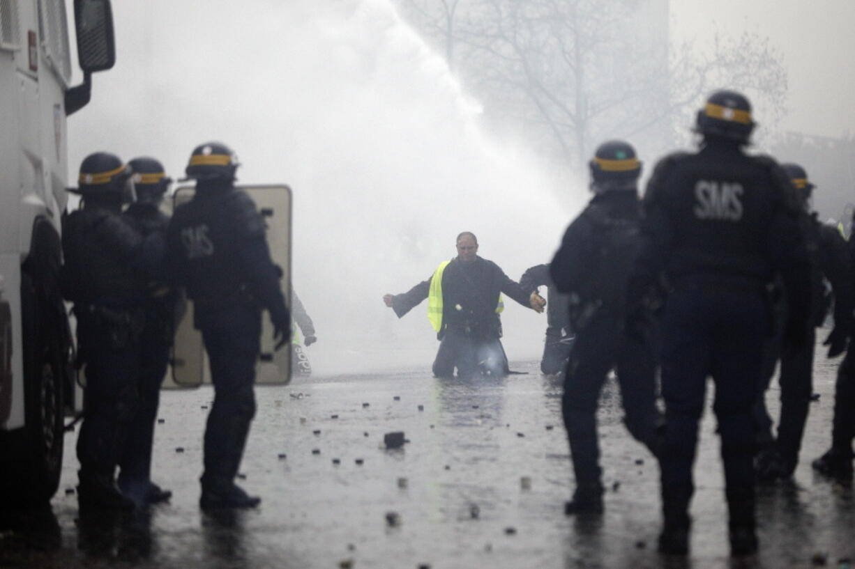 A demonstrators wearing a yellow jacket faces water cannons near the Champs-Elysees avenue during a demonstration Saturday, Dec.1, 2018 in Paris. French authorities have deployed thousands of police on Paris’ Champs-Elysees avenue to try to contain protests by people angry over rising taxes and Emmanuel Macron’s presidency.