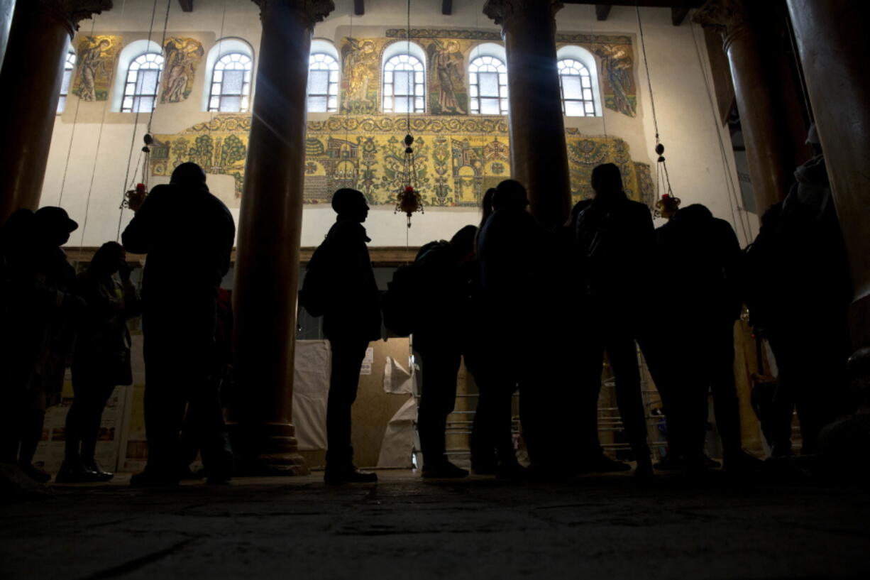 Visitors stand bellow a renovated part of a fresco inside the Church of the Nativity, built atop the site where Christians believe Jesus Christ was born, in the West Bank City of Bethlehem. City officials are optimistic that the renovated church will help add to a recent tourism boom and give a boost to the shrinking local Christian population.