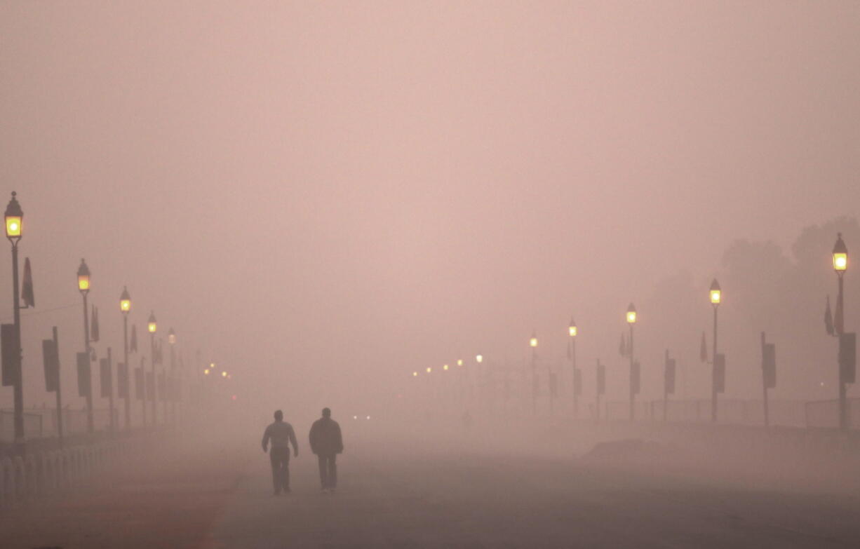 People take an early morning walk amid smog Wednesday in New Delhi, India, as the air quality hovered between severe and very poor.