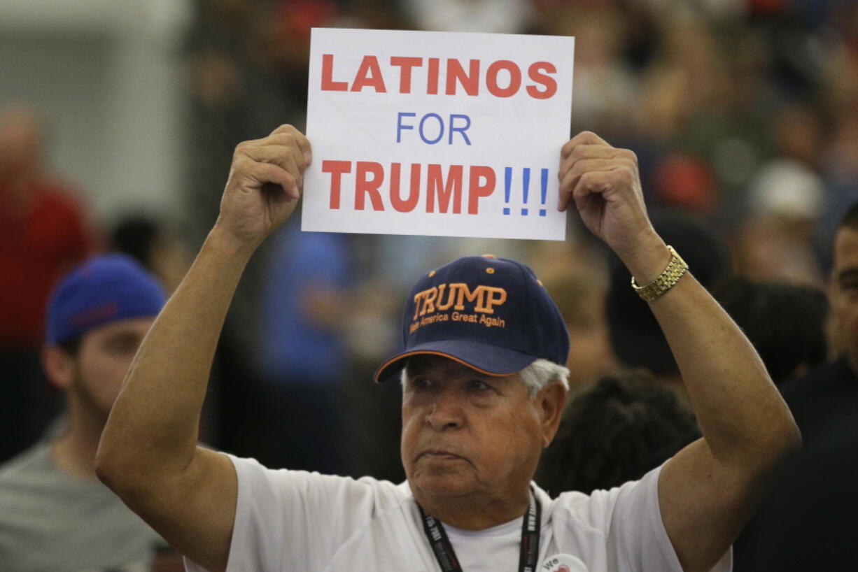 FILE - In this May 25, 2016, file photo, a man holds up a sign for then-Republican presidential candidate Donald Trump before the start of a rally at the Anaheim Convention Center, Wednesday, May 25, 2016, in Anaheim, Calif. Republicans are holding onto a steady share of the Latino vote in the Trump era. With a president who targets immigrants from Latin America, some analysts predicted a Latino backlash against the GOP. But it hasn’t happened. Data from AP’s VoteCast survey suggests Republicans are holding on to support from Latino evangelicals and veterans. (AP Photo/Jae C.