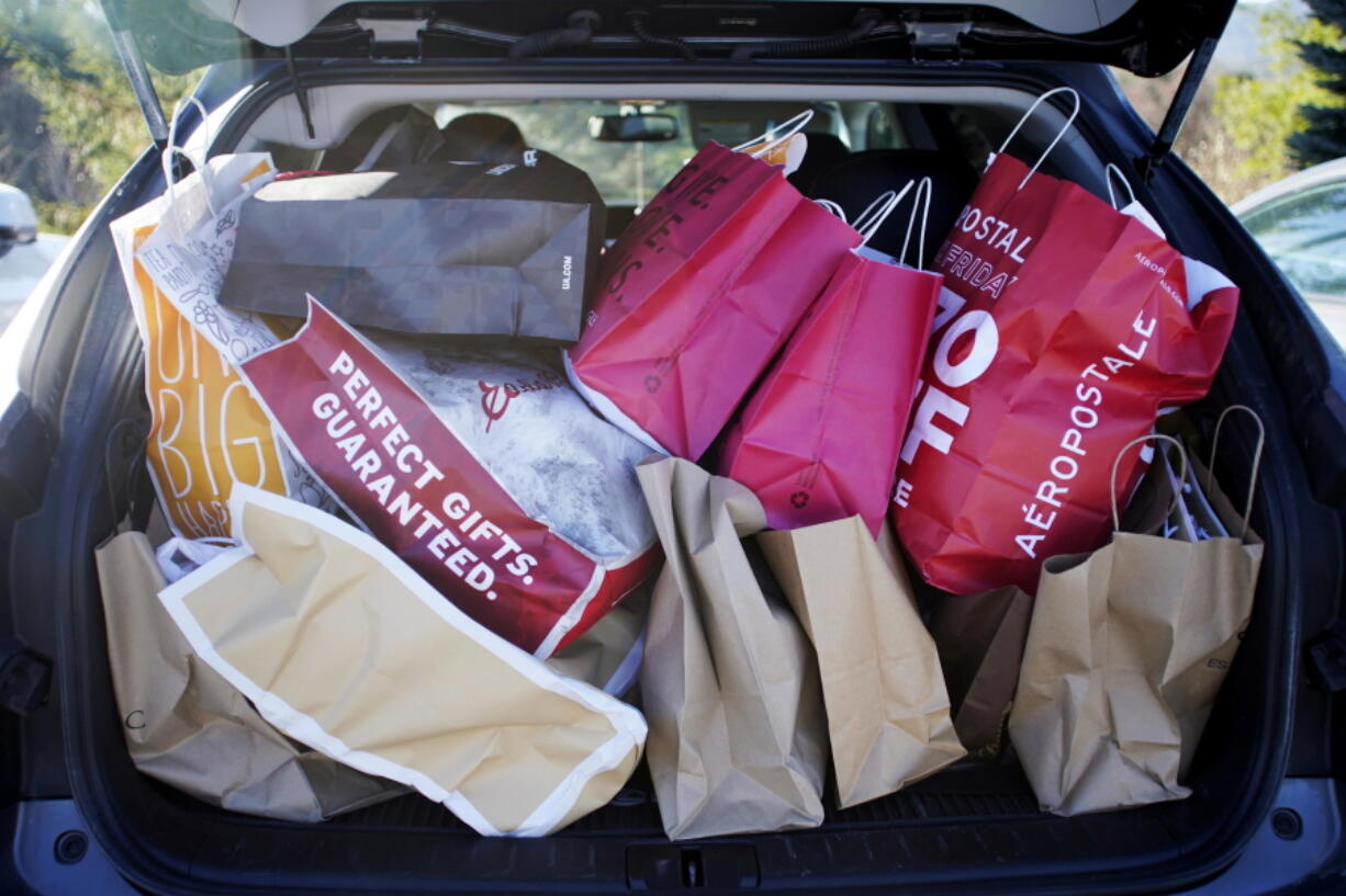 Shopping bags are stuffed into a car at Prime outlets on Black Friday in Lee, Mass. Last year, 65 percent of millennial shoppers put gifts on their credit cards.