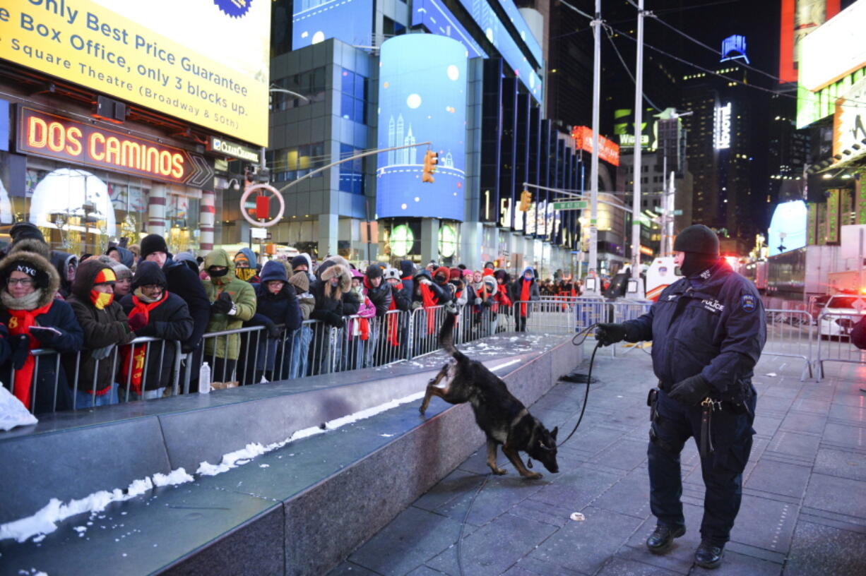 FILE - In this Dec. 31, 2017, file photo, a police K-9 unit patrols in New York’s Times Square where crowds were gathered for the annual New Year’s Eve celebration. The New York Police Department is adding a drone this year to the security forces it uses to protect the huge crowds celebrating New Year’s Eve in the city.