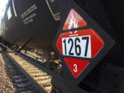 FILE - This Nov. 6, 2013 file photo shows a warning placard on a tank car carrying crude oil near a loading terminal in Trenton, N.D. The Trump administration vastly understated the potential benefits of installing more advanced brakes on trains that haul explosive fuels when it cancelled a requirement for railroads to begin using the equipment. A government analysis used by the administration to justify the cancellation omitted up to $117 million in potential reduced damages from using electronic brakes. Department of Transportation officials acknowledged the error after it was discovered by The Associated Press during a review of federal documents but said it would not have changed their decision.