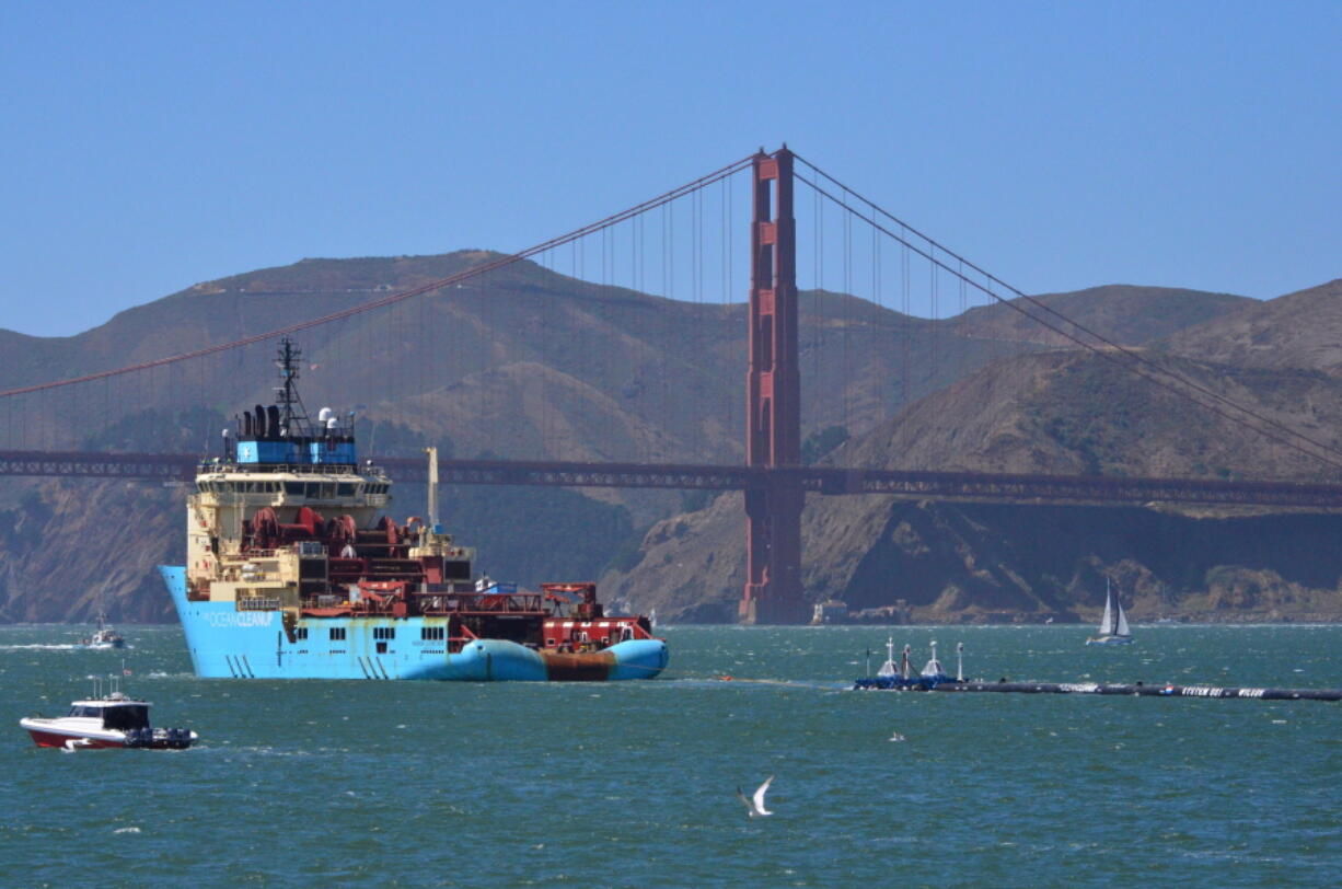 File - In this Sept. 8, 2018 file photo, a ship tows The Ocean Cleanup’s first buoyant trash-collecting device toward the Golden Gate Bridge in San Francisco en route to the Pacific Ocean. The trash collection device deployed to corral plastic litter floating between California and Hawaii in an attempt to clean up the world’s largest garbage patch is not collecting any trash. But Boyan Slat, who launched the Pacific Ocean cleanup project, told The Associated Press in an interview Monday, Dec. 17, 2018, he is confident the 2,000-foot (600-meter) long floating boom will be fixed.