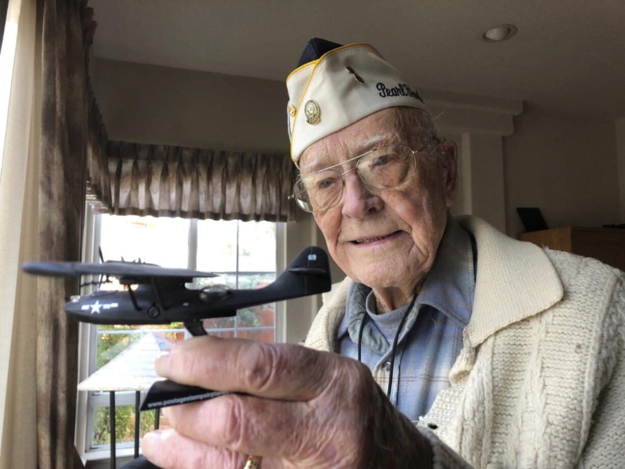 Retired U.S. Navy Cmdr. Don Long of Napa, Calif., holds a replica of the military seaplane he was aboard 77 years ago Friday, when Japanese warplanes attacked Hawaii.